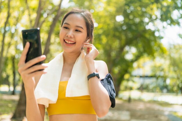 Sport attivo femminile asiatico sport panno impostazione smartphone giocando prepararsi per il suo allenamento di routine in esecuzione mattina sano stile di vita sorridente sport donna impostazione percorso di corsa nella sua mappa dell'applicazione