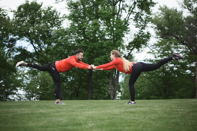 Sport uomo e donna che si allenano tenendosi per mano mentre si allenano nel parco