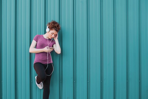 Sportiva con le cuffie e telefono sulla strada