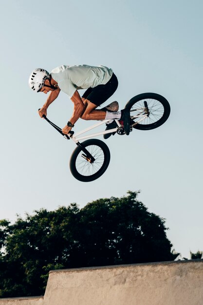 Sportivo che fa i salti estremi nella vista di angolo basso dello skatepark