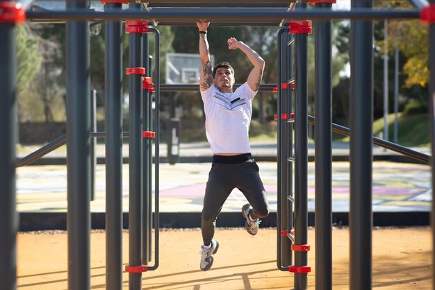 Sportivo che lavora in una giornata di sole. Uomo in abiti sportivi su campo sportivo all'aperto, attrezzatura da arrampicata. Sport, salute, concetto di allenamento