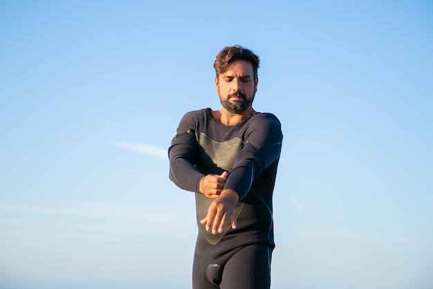 Sportivo concentrato che indossa la muta per il surf sulla spiaggia dell'oceano