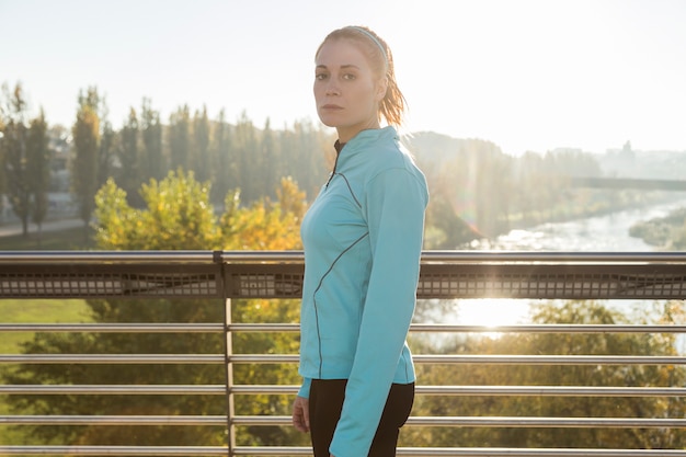 Sportswoman che propone con la natura di fondo