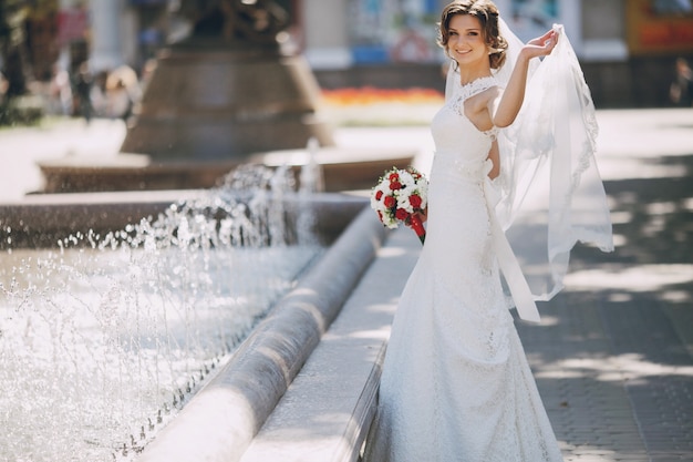 Sposa allegra tenendo il velo con la mano sinistra