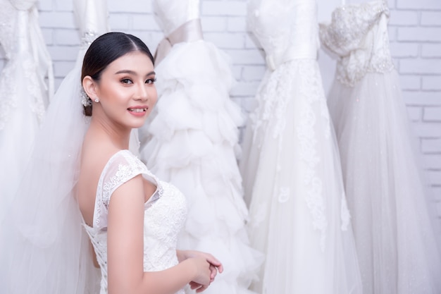 Sposa asiatica della giovane donna che prova sul vestito da sposa alle nozze moderne