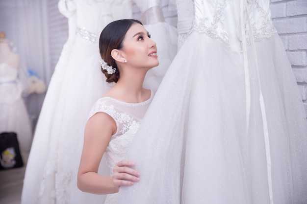 Sposa asiatica della giovane donna che prova sul vestito da sposa alle nozze moderne