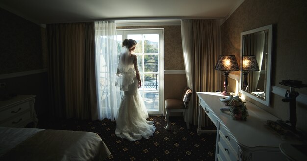Sposa che guarda attraverso la finestra dalla camera d'albergo