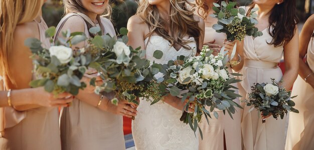 Sposa e damigelle con mazzi di fiori pastello stanno fianco a fianco