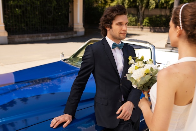 Sposa e sposo di vista laterale con i fiori