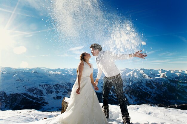 Sposa e sposo in amore lanciano neve sullo sfondo delle Alpi Courchevel