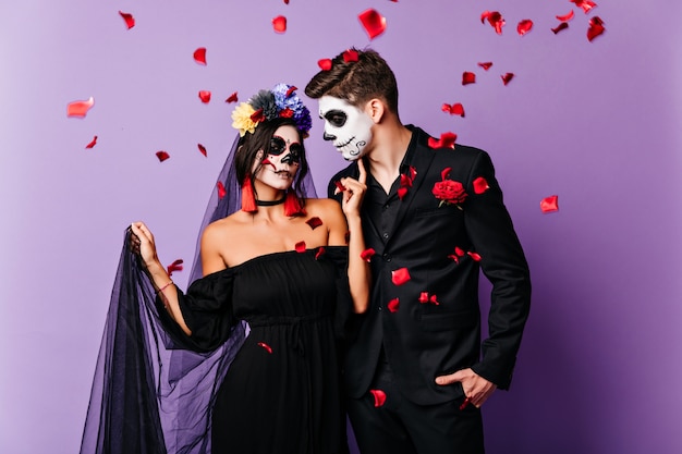 Sposa vampiro ispirata in posa in abito nero. Coppia morta che celebra il matrimonio a halloween.