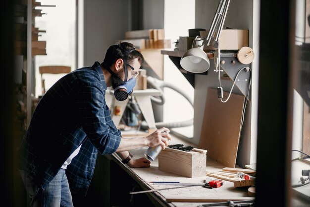 Spruzzo di vernice della holding dell'uomo e legno di verniciatura