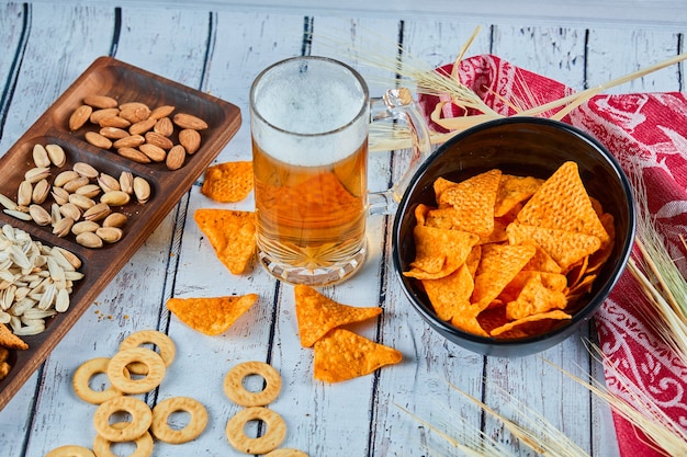 Spuntini assortiti, patatine e un bicchiere di birra sul tavolo blu.