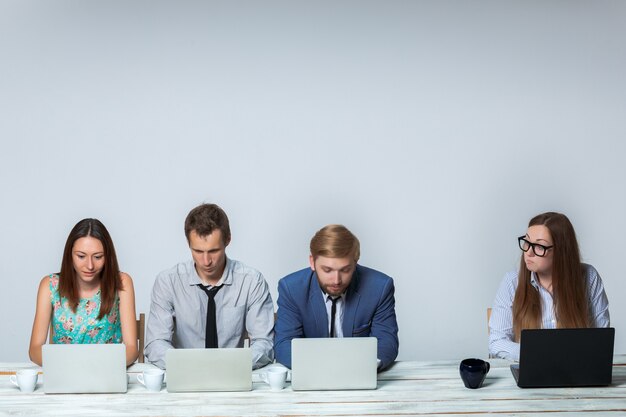 Squadra di affari che lavora insieme all'ufficio su sfondo grigio chiaro. tutti lavorano su laptop. immagine copyspace