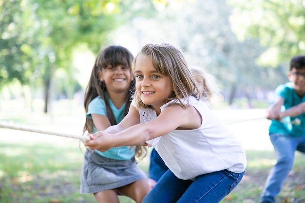 Squadra di bambini felici che tirano la corda, giocano al tiro alla fune, si godono le attività all'aperto. Gruppo di bambini che si divertono nel parco. Concetto di infanzia o lavoro di squadra