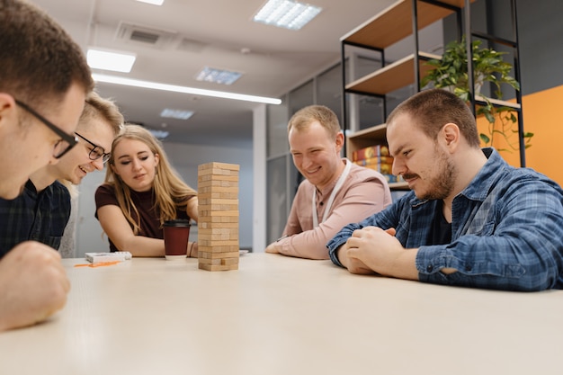 Squadra mista che gioca il gioco di legno dei blocchi nell'ufficio