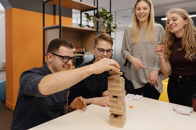 Squadra mista che gioca il gioco di legno dei blocchi nell'ufficio