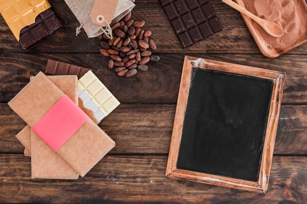 Stack di cioccolato, ardesia di legno bianco, fave di cacao e polvere sul tavolo