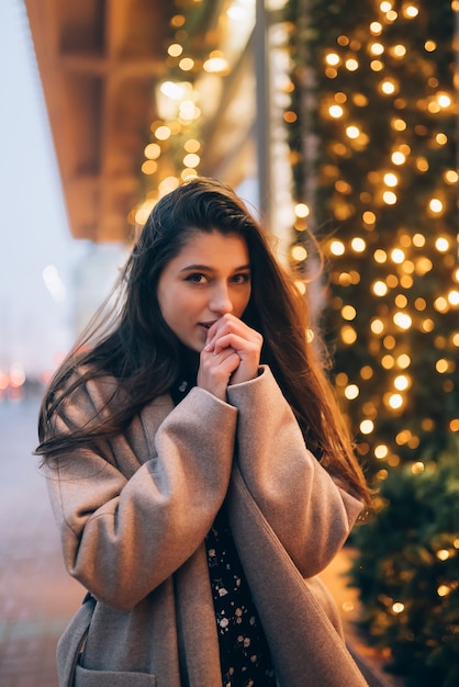 Stagione delle vacanze invernali. Natale, Anno Nuovo concetto. Donna dalla vetrina illuminata sulla strada della città.