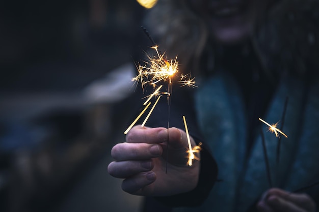 Stelle filanti accese nelle mani di una giovane donna al buio