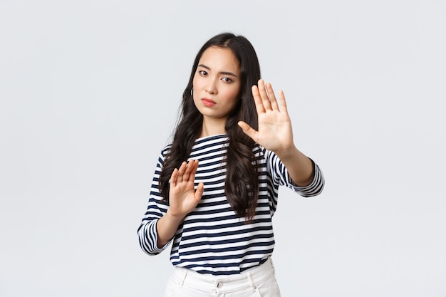 Stile di vita, bellezza e moda, concetto di emozioni delle persone. Donna infastidita che si sente a disagio a essere fotografata, chiedendo di spegnere la fotocamera, alzando le mani sulla difensiva, proteggendo il viso dalla torcia elettrica