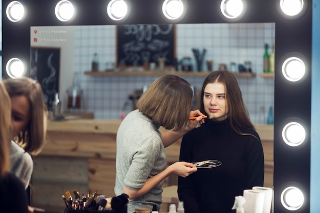 Stilista che applica cosmetico sulla donna adorabile