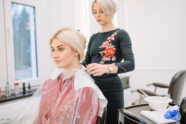 Stilista sicuro che prepara ragazza per colorazione