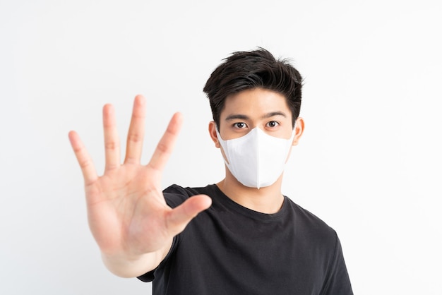 Stop Civid-19, uomo asiatico che indossa la maschera per il viso mostra il gesto delle mani per fermare l'epidemia di virus corona