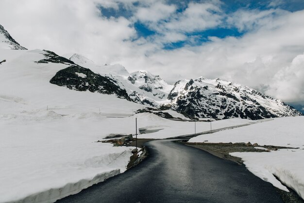 Strada asfaltata in montagne nevose delle Alpi nell&#39;ora legale