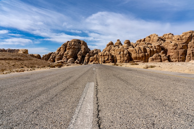 Foto gratuito strada che passa tra grandi scogliere sotto un cielo blu chiaro