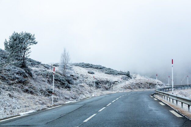 Strada circondata da montagne innevate coperte di nebbia