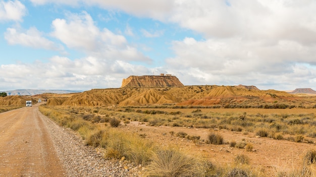 Strada in un deserto con vista su un monolite sotto un cielo nuvoloso