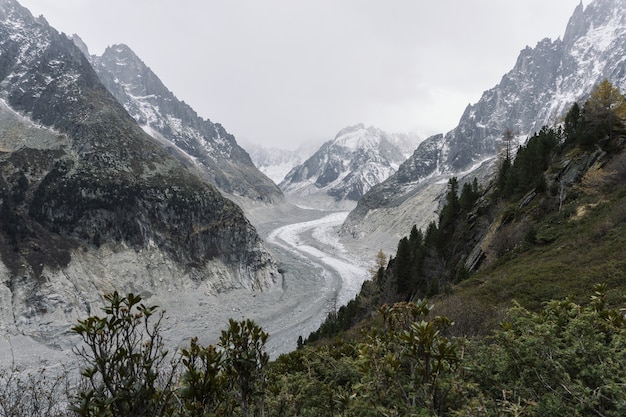 strada sinuosa in mezzo a montagne innevate sotto un cielo nuvoloso