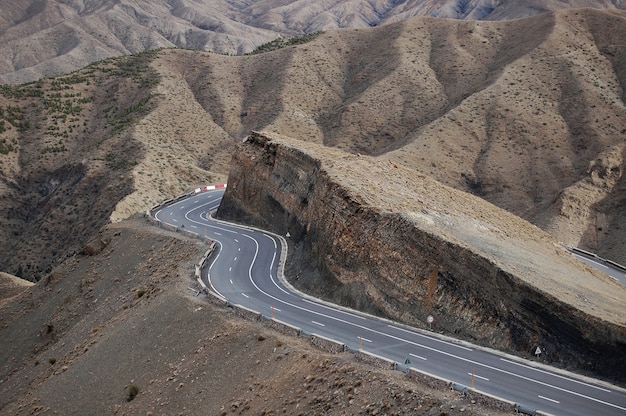 Strada sinuosa intorno alla scogliera con le montagne