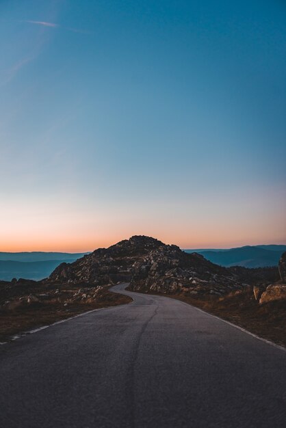 Strada stretta che conduce a una grotta rocciosa sotto il bel cielo al tramonto
