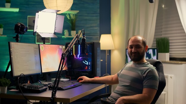 Streamer uomo che guarda la telecamera e sorride mentre la chat in streaming è aperta