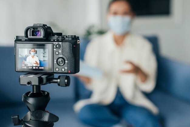 Streaming domestico della donna sfocata di vista frontale mentre indossa la maschera facciale