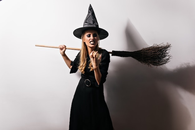Strega arrabbiata che pensa a qualcosa di malvagio. mago femminile in abito nero lungo che esprime rabbia in halloween.