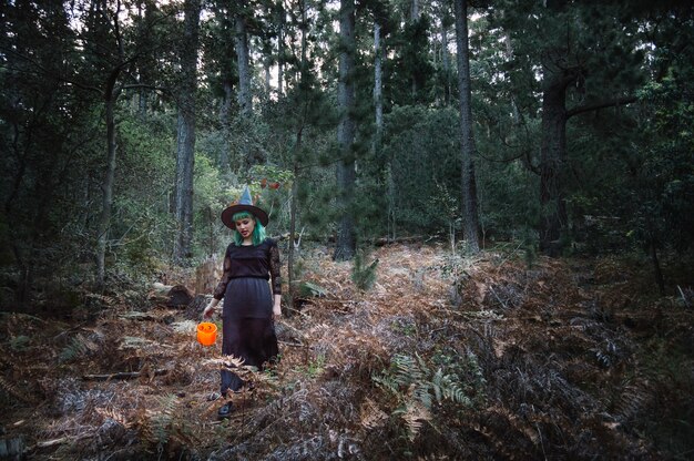 Strega con benna che cammina nella foresta