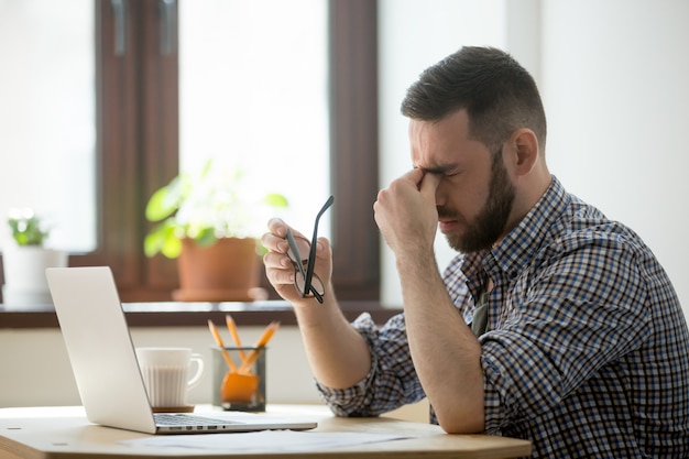 Stressato maschio massaggio ponte naso soffre di mal di testa