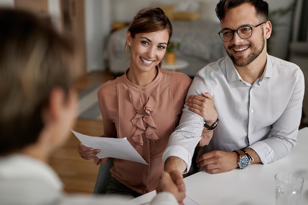 Stretta di mano delle coppie felici con il loro consulente finanziario dopo l'incontro