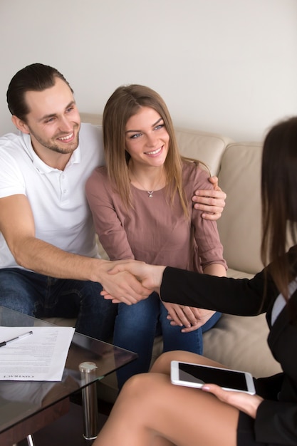 Stretta di mano dopo il riuscito affare, coppia e contratto di firma della femmina, verticale