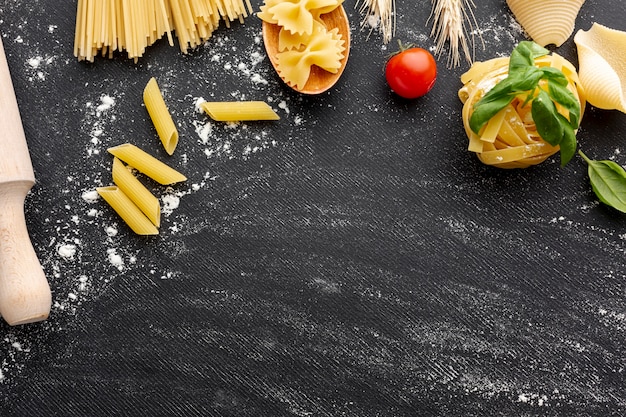 Struttura cruda di disposizione della pasta su fondo nero con lo spazio della copia