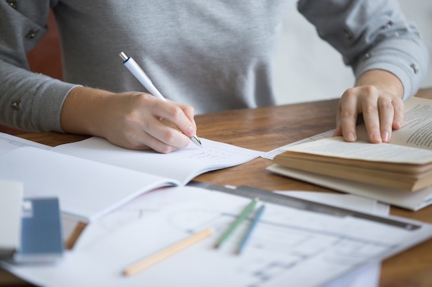 Student hands femminile che esegue un compito scritto in un copybook