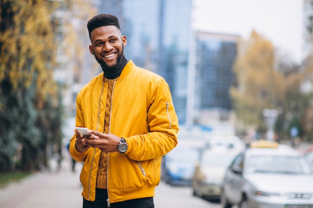 Studente afroamericano camminando per la strada e parlando al telefono