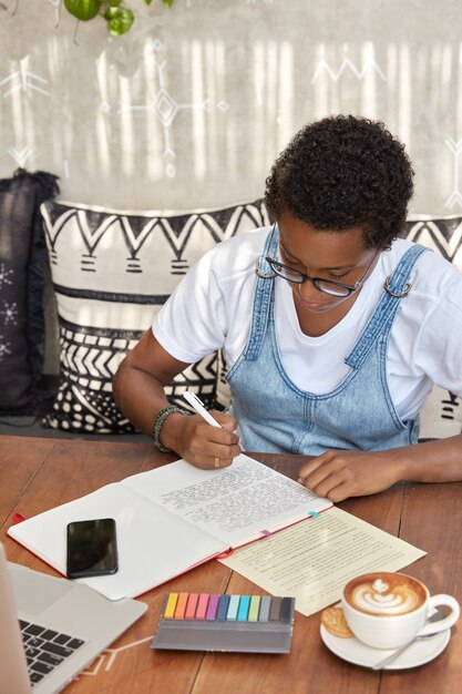 Studente afroamericano fa esercizi di traduzione, riscrive le frasi sul taccuino