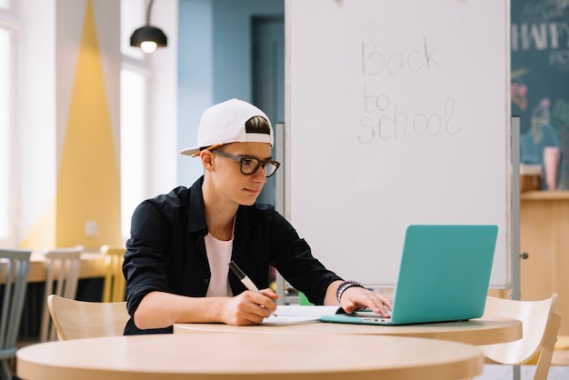 Studente alla moda che guarda il computer portatile