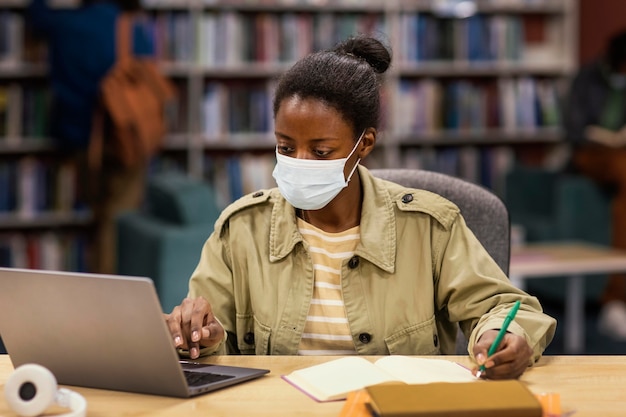 Studente che indossa una maschera facciale in biblioteca