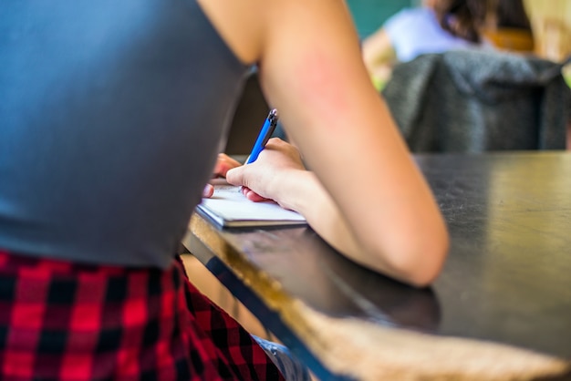 Studente che studia scrivere note in un taccuino in una tabella