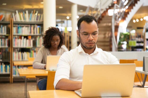 Studente concentrato dell'uomo che lavora al computer